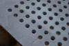A close-up view of a cast iron grate with evenly spaced circular holes. Produktbild-Vorschau
