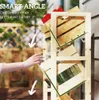 A person's hand reaching for a drink from a wooden shelving unit outdoors. Produktbild-Vorschau