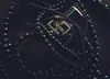 A close-up shot of a bottle of perfume surrounded by black beads. Anteprima dell’immagine prodotto