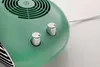A close-up shot of the top section of a green electric heater, showing two silver control knobs and a ventilation grill. Podgląd zdjęcia produktu