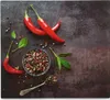 A top-down view of red chili peppers, peppercorns in a bowl and on a spoon, and bay leaves on a dark, textured surface. Náhled obrázku produktu
