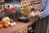 A person is cooking in a kitchen with a glass stove top protector featuring a poppy field image. Produktbild-Vorschau