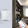 A smart thermostat is mounted on a wall next to a bookshelf, and a smartphone is being used to control it. Anteprima dell’immagine prodotto