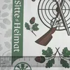 A close-up of a patterned paper tablecloth with hunting and nature motifs, including a target, shotguns, acorns, and oak leaves. A ruler is visible at the bottom. Produktbild-Vorschau