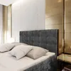 A close-up view of a bed with a tufted headboard and pillows. Produktbild-Vorschau