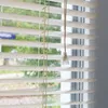 Close-up of white horizontal blinds with a pull cord. Produktbild-Vorschau
