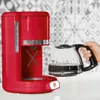 A red coffee maker with a glass carafe being held by a hand. Anteprima dell’immagine prodotto