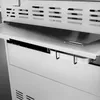 A close-up, black and white shot of the interior of a gas grill, focusing on the drip tray and heat shield. Produktbild-Vorschau