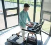 A man is using a treadmill with a laptop on a desk attachment. Produktbild-Vorschau