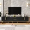 A modern living room setup featuring a black TV stand with gold accents, a large black television, and decorative items. Produktbild-Vorschau