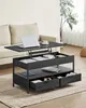 A lift-top coffee table with storage is shown in a living room setting next to a sofa, with a laptop on its raised surface. Náhled obrázku produktu