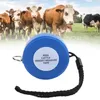 A blue measuring tape for pigs and cattle is shown in the foreground, with a herd of cows in the background grazing in a field. Náhľad obrázku produktu