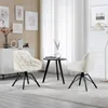 Two cream-colored chairs and a small black table are arranged in a living room setting with artwork on the wall and sheer curtains in the background. Náhľad obrázku produktu