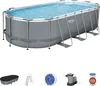 An oval-shaped above-ground swimming pool filled with blue water, supported by a metal frame. Below the pool are several accessories: a pool cover, a ladder, a filter pump, and a filter cartridge. Anteprima dell’immagine prodotto