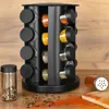 A black spice rack organizer with 16 glass containers filled with various spices, placed on a wooden surface. Produktbild-Vorschau
