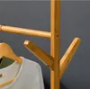 A close-up view of a wooden coat rack with a white shirt hanging on it. Produktbild-Vorschau
