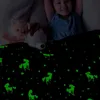 Schwarze, im Dunkeln leuchtende Decke mit grünen Einhorn- und Sternenmustern, die ein Kind und zwei Stofftiere im Bett bedeckt Produktbild-Vorschau
