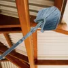 A telescopic duster is being used to clean cobwebs from the ceiling of a structure with wooden beams and corrugated metal roofing. Podgląd zdjęcia produktu