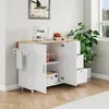 A white kitchen cart with a wooden countertop is shown in a room with a window and a plant. Podgląd zdjęcia produktu