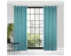 A pair of turquoise curtains hanging in front of a large window with a city view. Voir les images du produit
