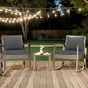 Two outdoor rocking chairs with dark gray cushions and a small side table are set up on a wooden deck at dusk, with string lights overhead. Náhled obrázku produktu