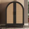 A black arched cabinet with rattan doors and dark legs, placed in a room setting. Produktbild-Vorschau
