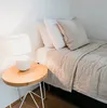 A bedside table with a lamp next to a bed with pillows and a duvet. Voir les images du produit
