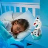 A young girl sleeping in bed next to an Olaf night light. Produktbild-Vorschau