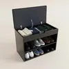 A shoe cabinet with a storage compartment on top, filled with folded clothes and gloves. The cabinet has three shelves below, holding various shoes. Náhľad obrázku produktu