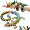 A person's hand and arm are holding and wearing a colorful, crystal-like dragon figurine. Produktbild-Vorschau