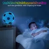A young boy sleeps peacefully in bed next to a glowing soccer ball night light. Produktbild-Vorschau