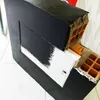 A black electrical distribution box with a partially painted white door is shown. The interior reveals brickwork and orange insulation. Produktbild-Vorschau