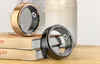 Two smart rings are displayed on a stack of books next to a decorative vase. Produktbild-Vorschau