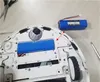 The underside of a white robot vacuum cleaner is shown, with the battery removed and placed next to it. Tools like scissors and a screwdriver are also visible. Produktbild-Vorschau