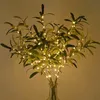 A bouquet of artificial olive branches with LED lights in a glass vase. Produktbild-Vorschau
