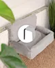 A grey, plush pet bed is placed on a radiator, with a green plant in the foreground. Náhľad obrázku produktu