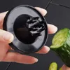 A hand holding a black vegetable spiralizer tool and a cut cucumber. Produktbild-Vorschau
