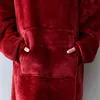 A close-up view of a person wearing a red hoodie blanket, showing the pocket and sleeves. Produktbild-Vorschau