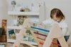 A toddler plays on a wooden climbing triangle in a room with bookshelves. Voir les images du produit