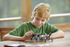 A young boy is building a LEGO set on a wooden table. Náhled obrázku produktu