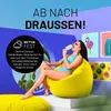 A woman sits on a yellow beanbag chair, eating an ice cream, with a tropical-themed background and text promoting outdoor use. Produktbild-Vorschau