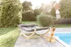 A hammock lounge bed with a cover is placed on a patio next to a swimming pool. Produktbild-Vorschau