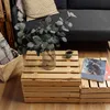A living room scene with a sofa, wooden crates used as a coffee table, a vase with eucalyptus, and a magazine. Náhľad obrázku produktu