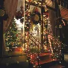 A festive Christmas display outside a shop, featuring a decorated Christmas tree, garlands of lights, and a wreath. Produktbild-Vorschau