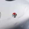 A close-up shot of a red button on a silver metallic surface. Podgląd zdjęcia produktu
