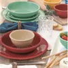 A table setting with plates, bowls, napkins, cutlery, bread, cheese, and olives. Produktbild-Vorschau