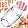 A glass jar with a red and white checkered lid, surrounded by various fresh vegetables and herbs. Podgląd zdjęcia produktu