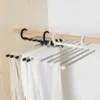 Schwarz-weiße mehrstöckige Hosenbügel, die weiße und beige Hosen an einer Holzschrankstange halten Náhľad obrázku produktu
