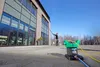 A person is cleaning the windows of a modern building with a long pole, using a water purification system. Produktbild-Vorschau