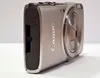A close-up side view of a silver Canon digital camera. Produktbild-Vorschau